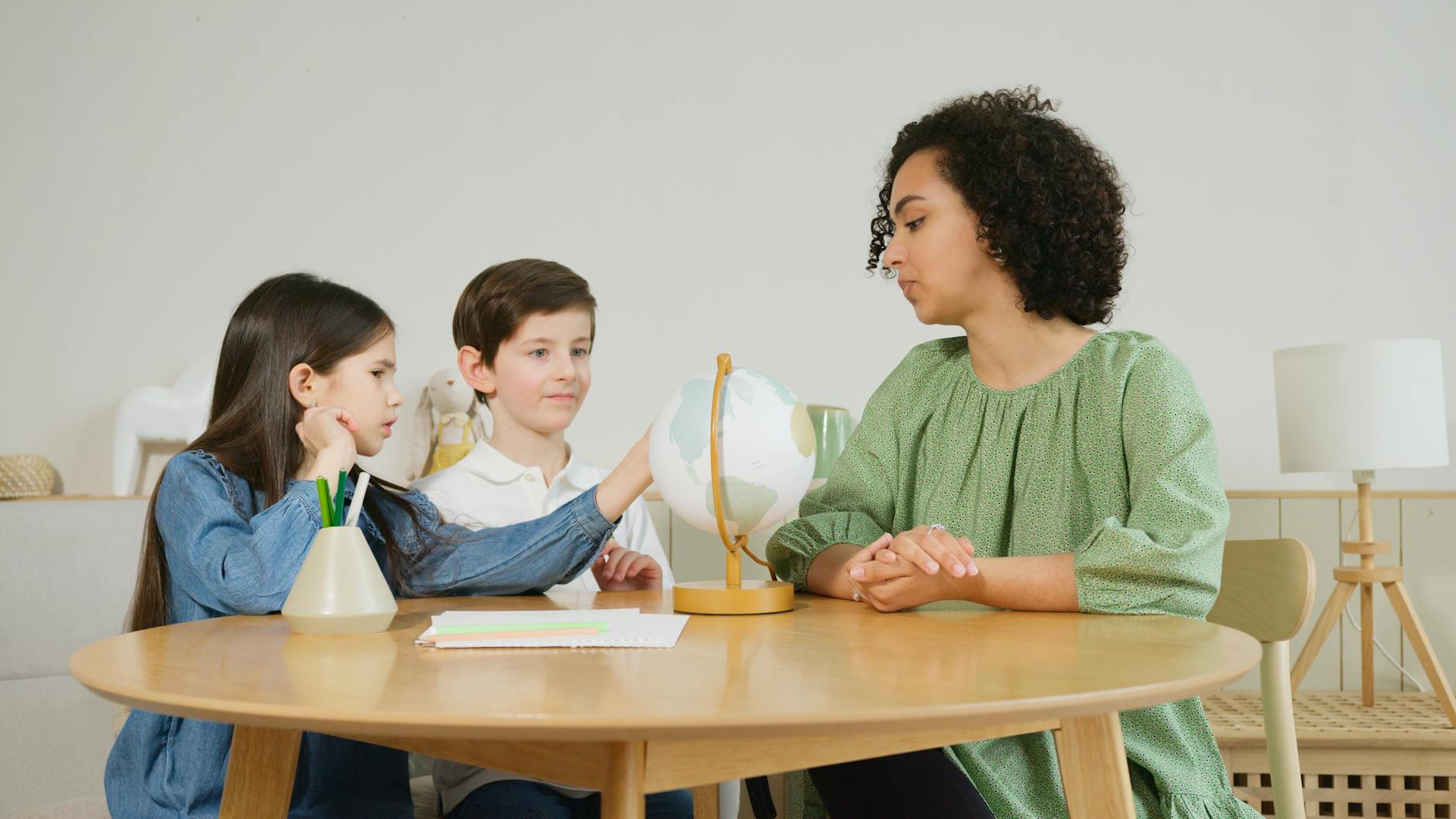 kids sitting beside the curly haired woman on the wooden table