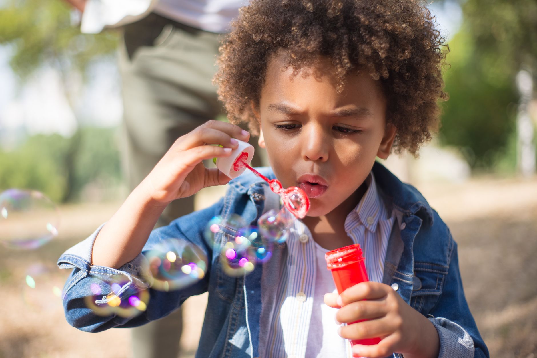 boy with curly hair blowing bubbles